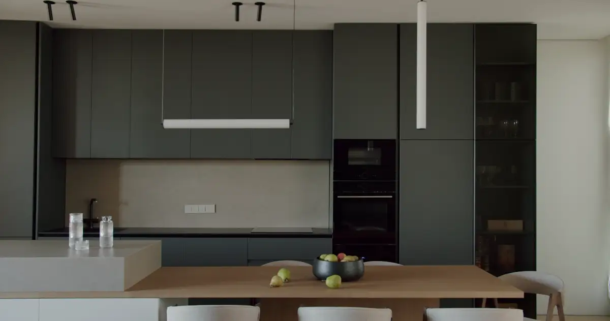 Kitchen with deep green gray cabinets and a wood table