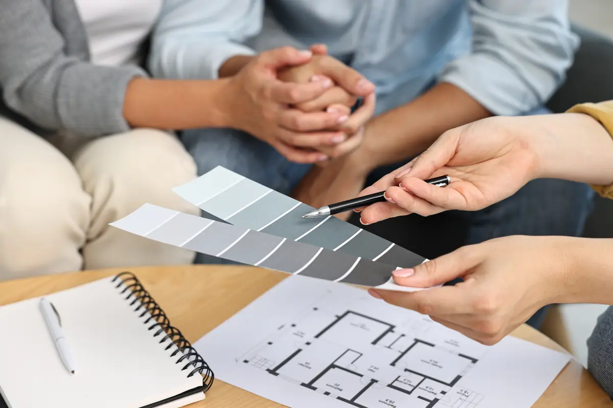 Homeowner reviewing gray paint swatches with plans