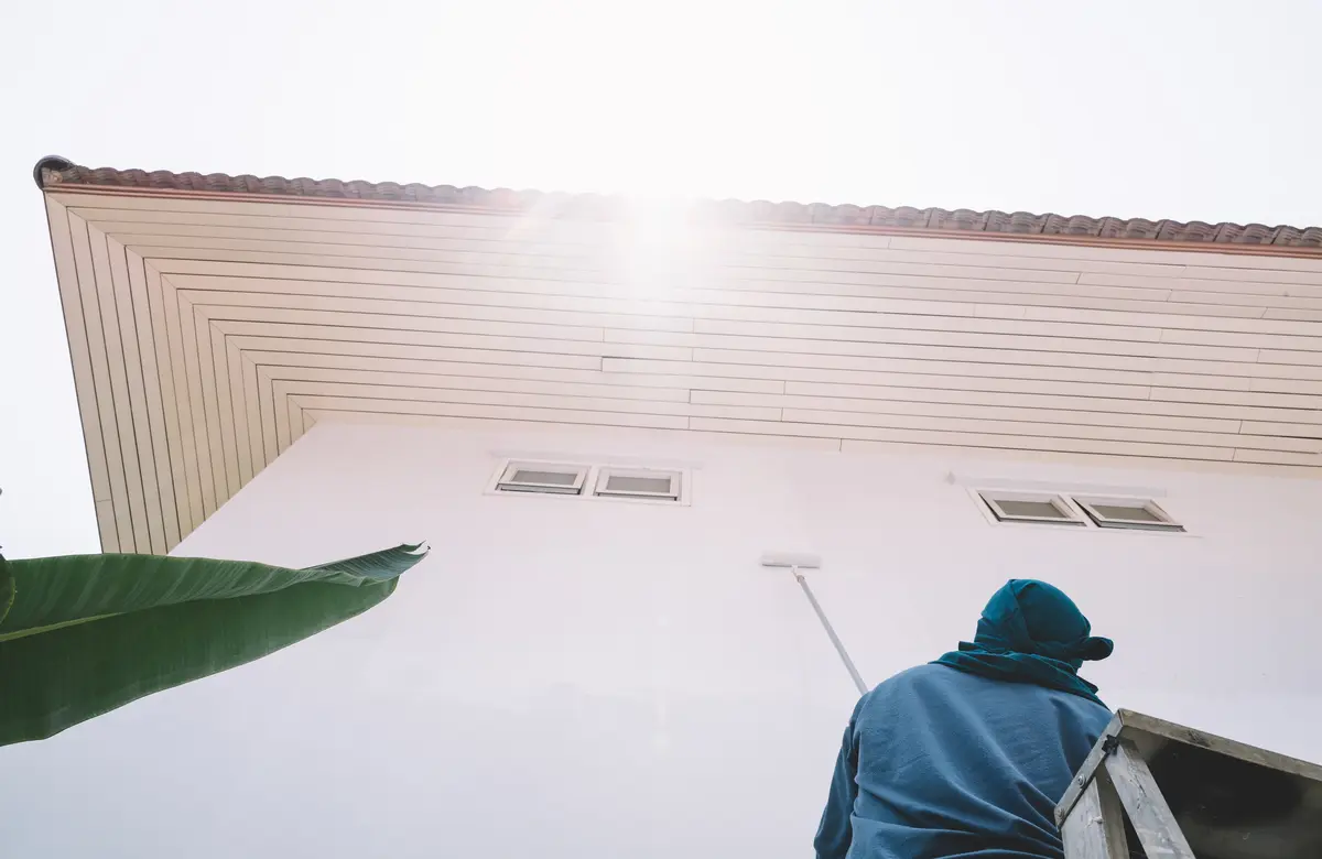 Painter rolling a soffit on a white home