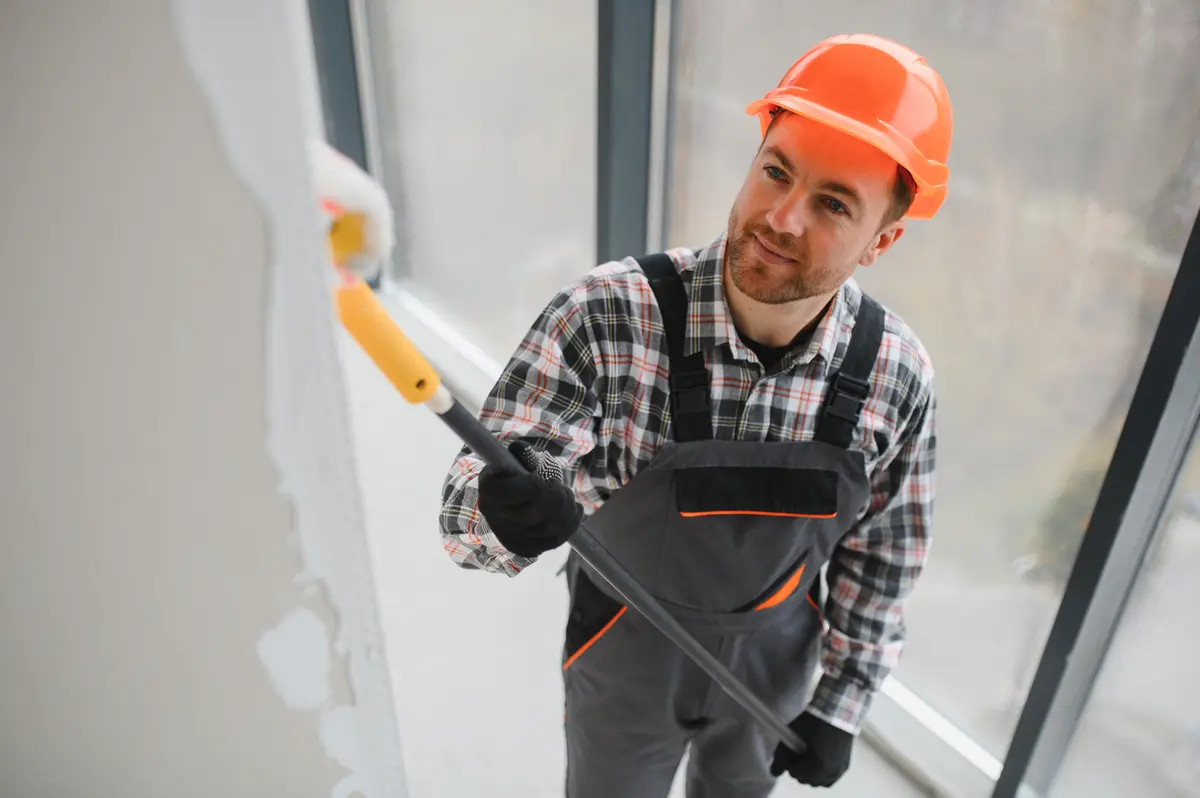 Painter rolling white paint on an interior wall