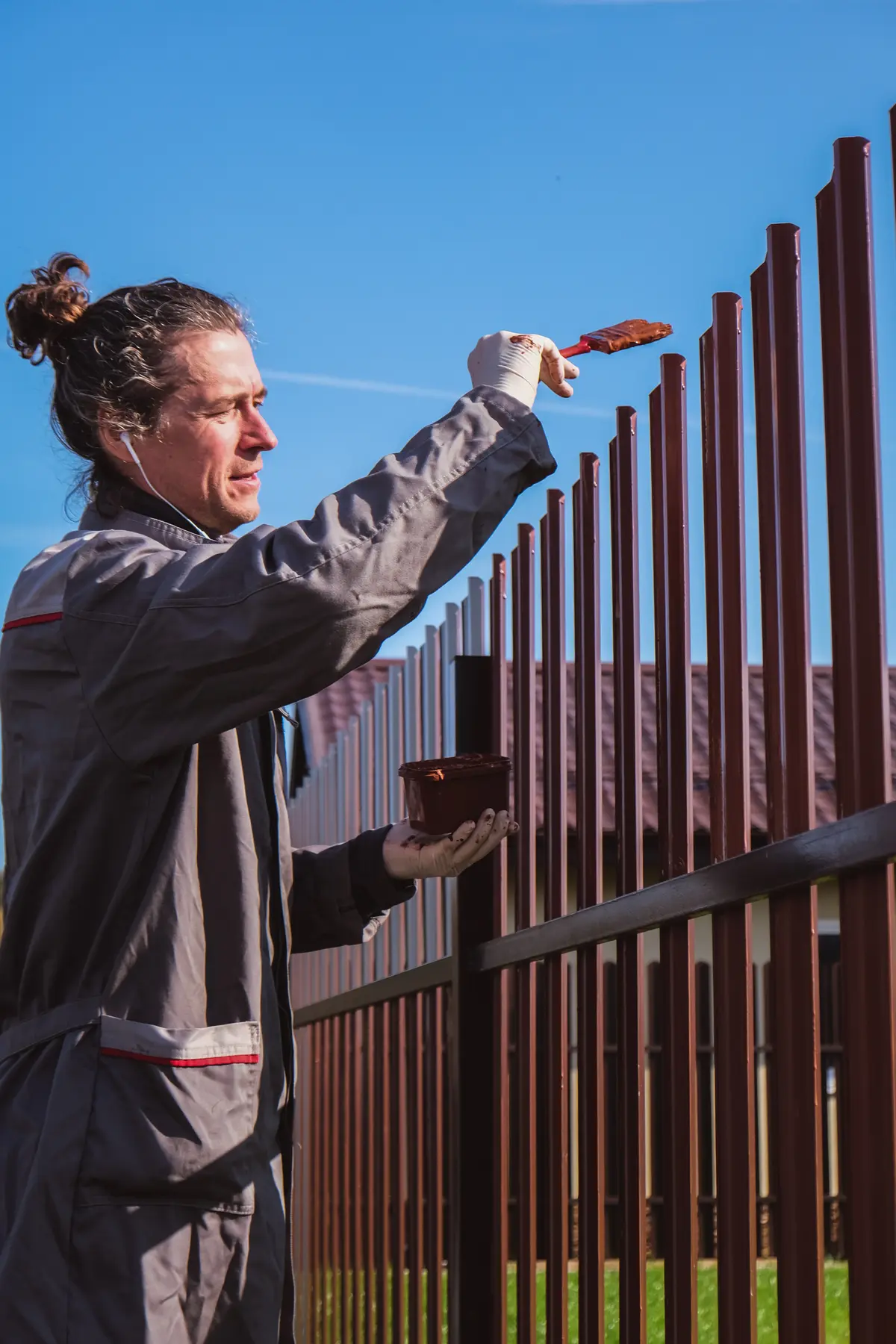 Painter brushing paint onto a metal fence