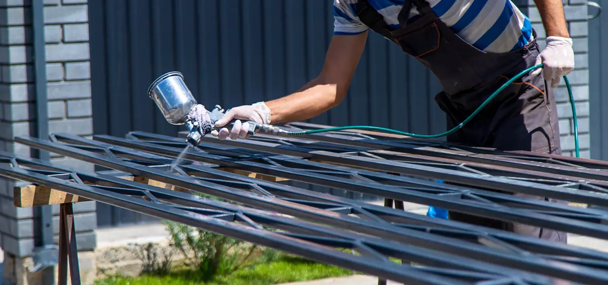 Painter spraying paint on an iron railing