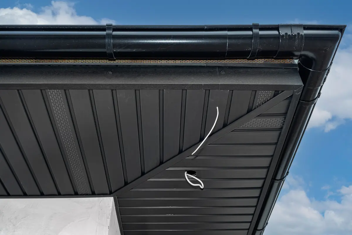 Dark painted soffit and gutter under a roof edge