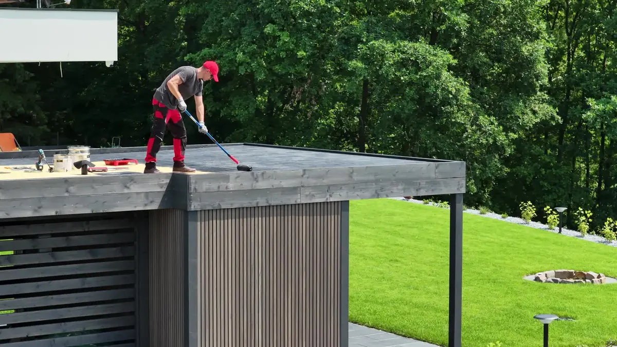 Painter applying roof coating with a long roller