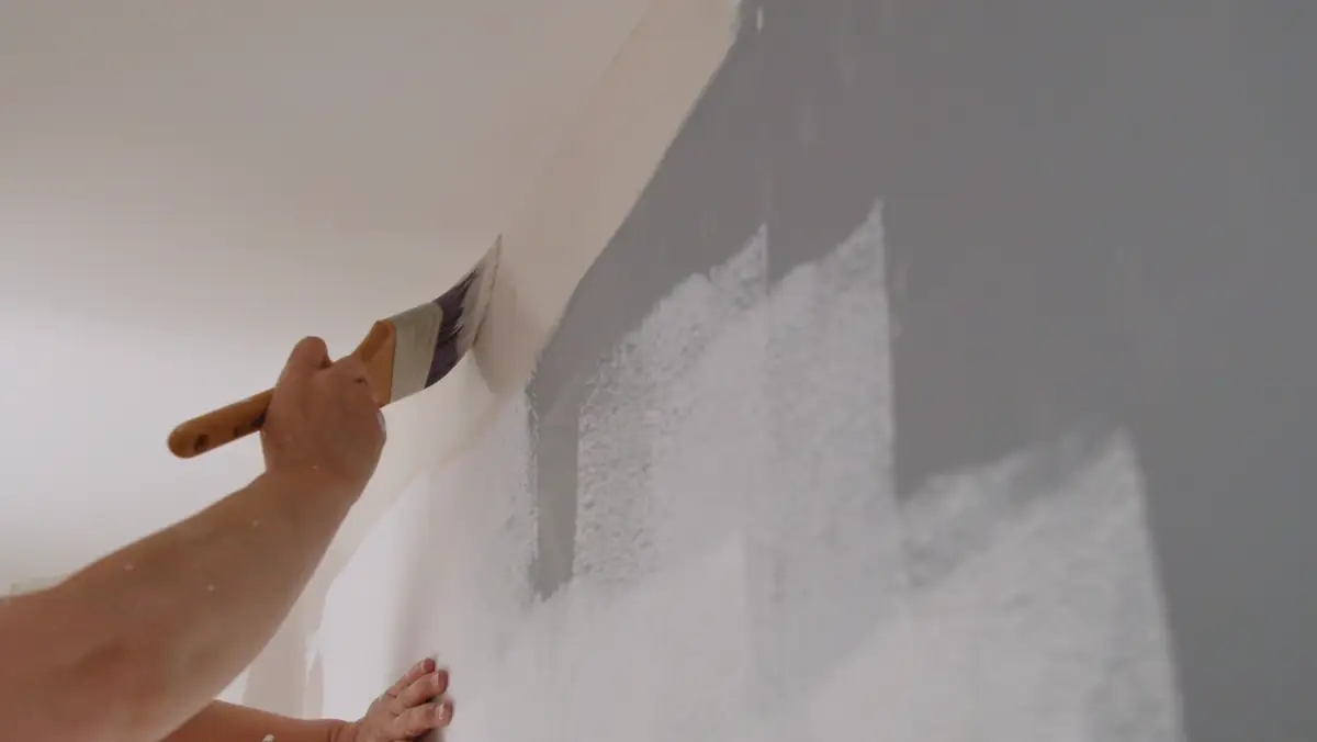 Brush cutting a clean line between gray and white paint