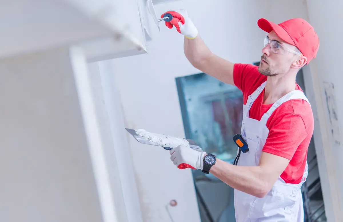 Worker repairing a ceiling with spackle