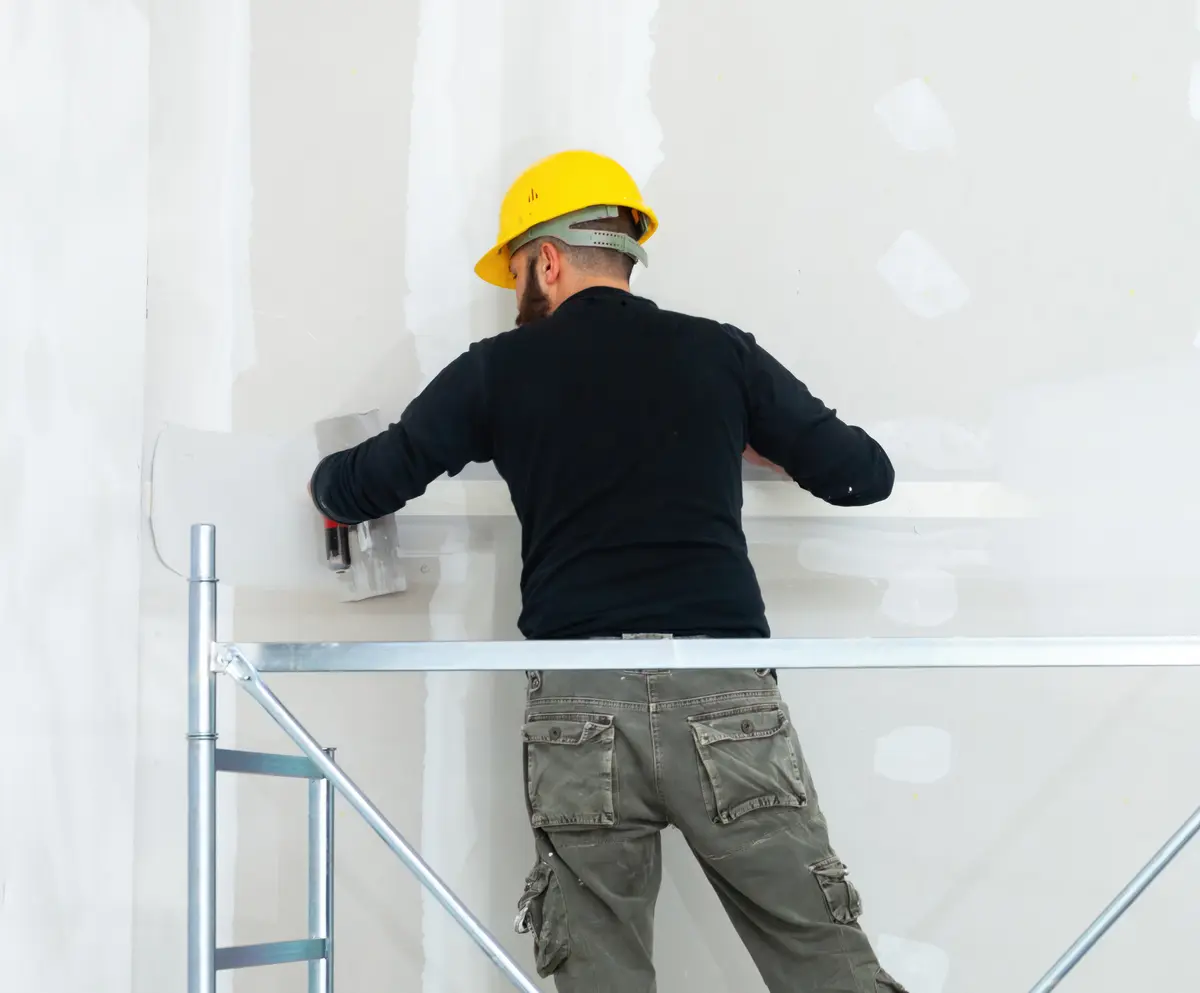 Worker coating an exterior wall from scaffolding