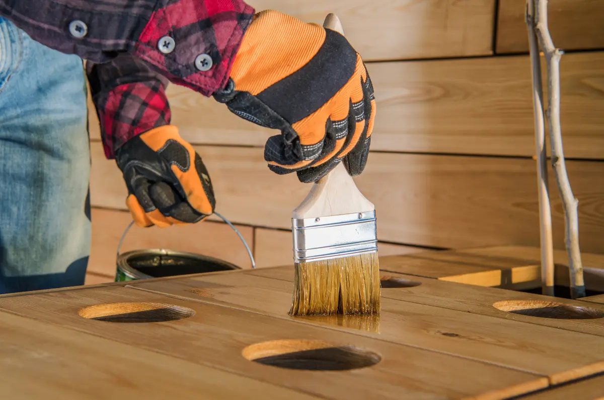 Brush applying stain to a wood table top