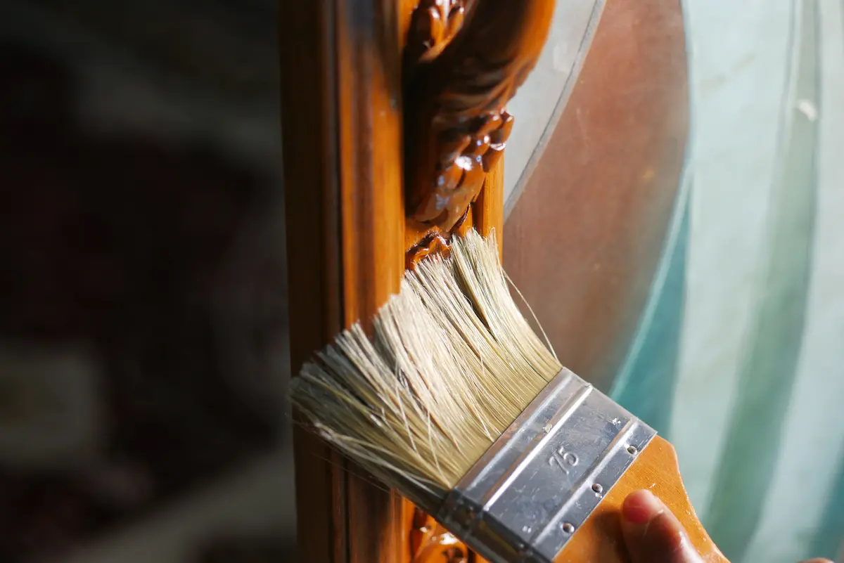 Brush applying varnish to a wood frame