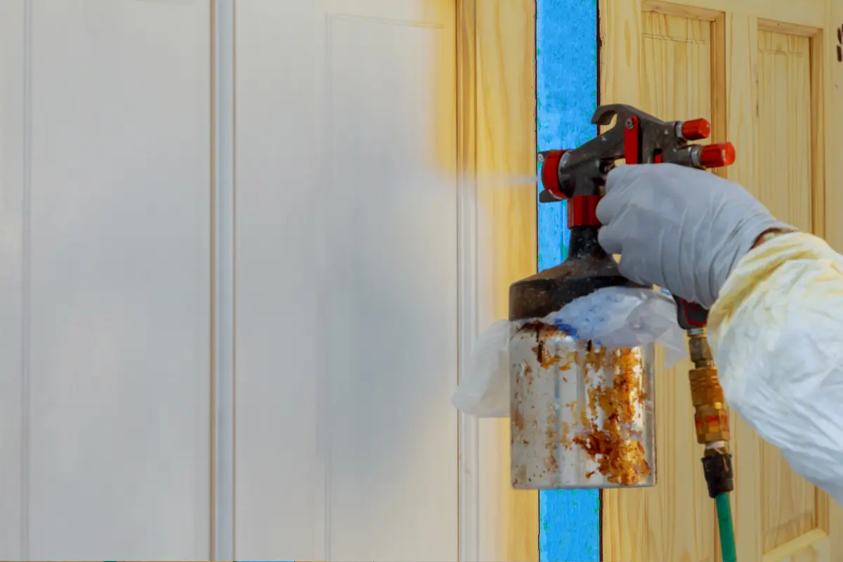 Painter spraying a protective finish on a wood door